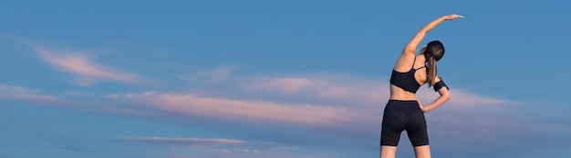 Female posing in sportswear on sky background the middle part of the body