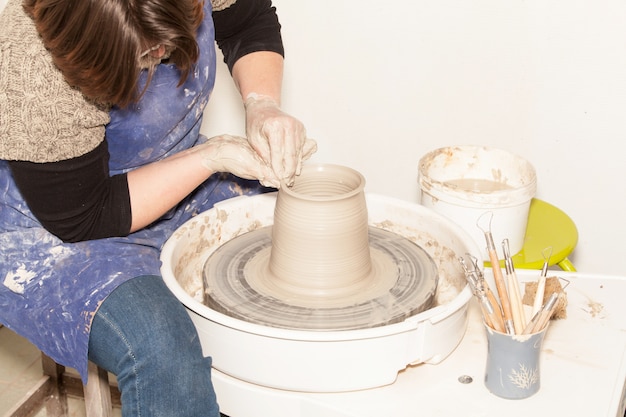 Женщина Поттер создает глиняную банку на гончарном круге