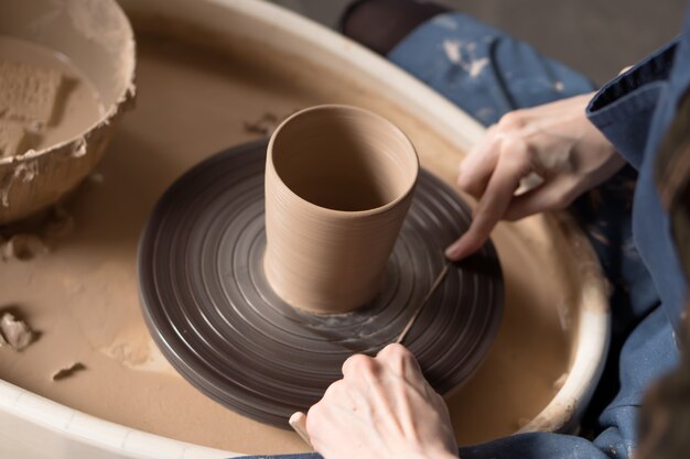 female potter cuts a finished product from a potters wheel