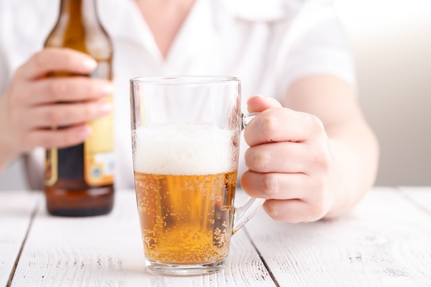 La birra di versamento femminile in tazza di vetro, si rilassa il concetto