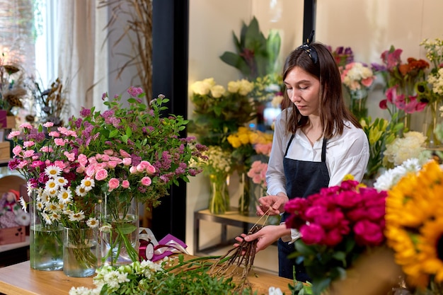 女性のプロの花屋が野花のアレンジメントを準備します。花屋