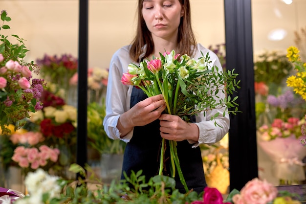 女性のプロの花屋が野花のアレンジメントを準備します。花屋