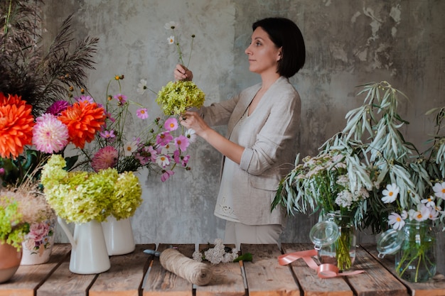 Female professional florist prepares the arrangement of wild flowers.