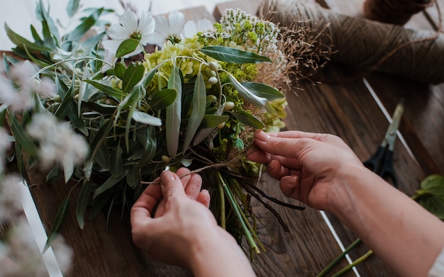 女性のプロの花屋が野生の花のアレンジを準備します。