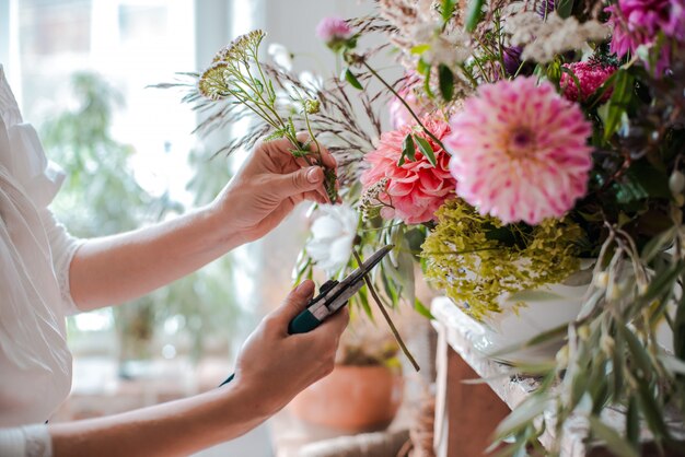 野生の花のアレンジメントを準備する女性専門の花屋。