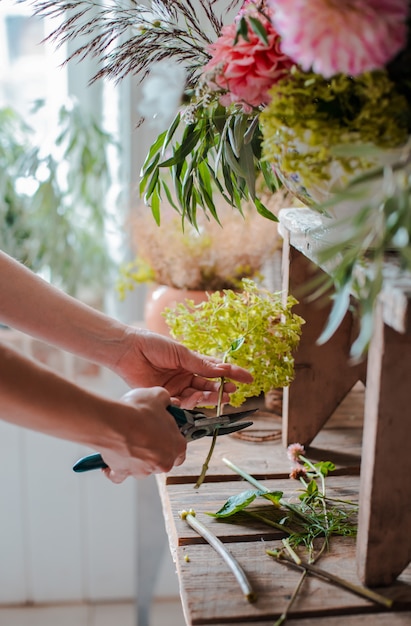 野生の花のアレンジメントを準備する女性専門の花屋。