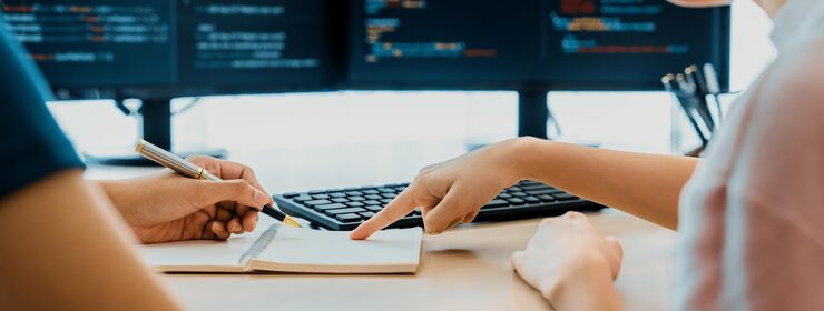 Photo female programer taking a note while young skilled web developer present program while computer displayed program code at modern office company java script web design concept burgeoning