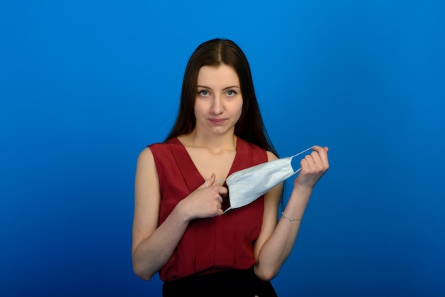 female in protective medical mask and blue gloves on blue background.