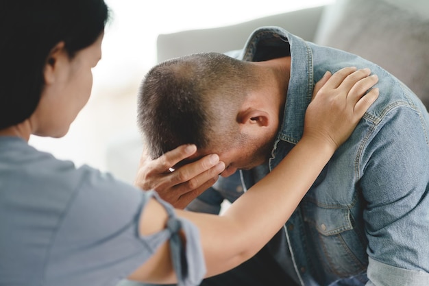 女性心理学者の友人が座って、精神的な憂鬱な男性を応援するために肩に手を置きます