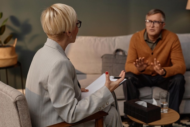 Female psychologist listening to man during therapy