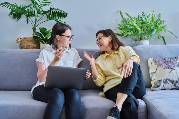 Female psychologist and middle aged woman patient sitting together on couch in office