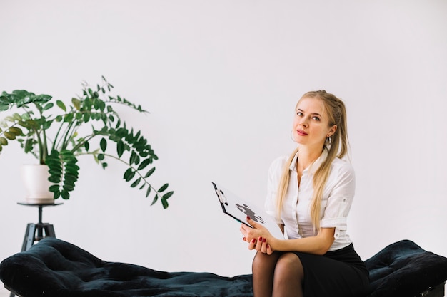 Photo female psychologist sitting on couch holding rorschach inkblot test paper on clipboard