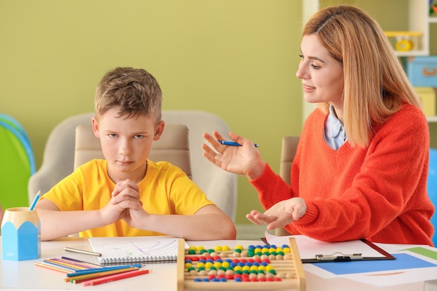 Female psychologist working with boy suffering from autistic disorder