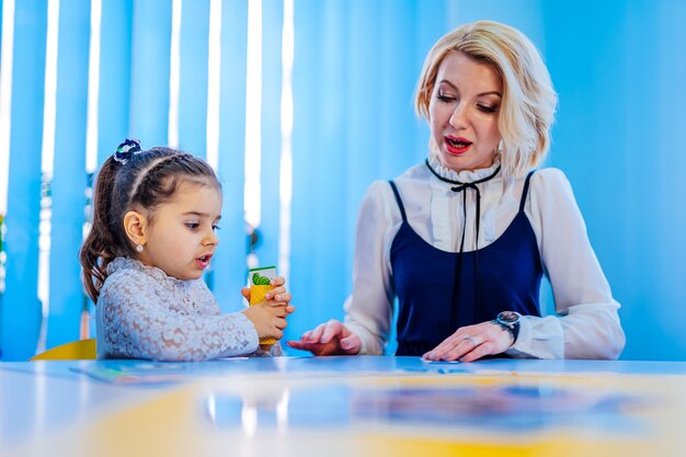 Female psychologist working with cute little girl in office