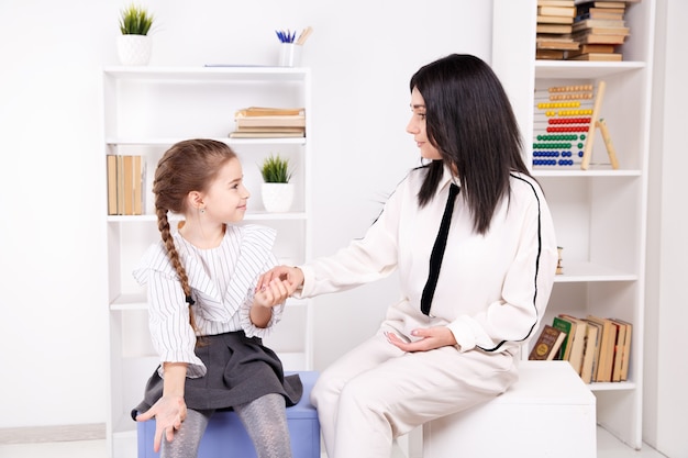 Female psychologist working with girl in the white cabinet.