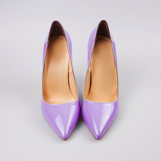 Female purple high-heeled shoes over grey