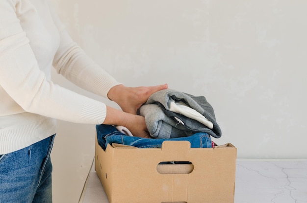 Female put gather clothes in cardboard box make donation to needy people