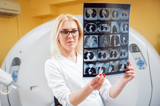 Female radiologist looking at x-ray in the room of computed tomography.