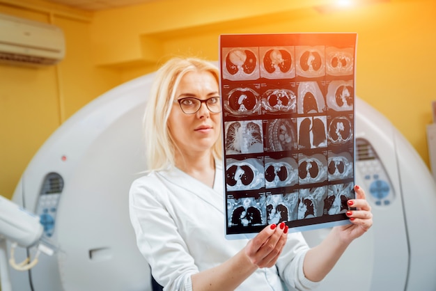 Female radiologist looking at x-ray in the room of computed tomography.