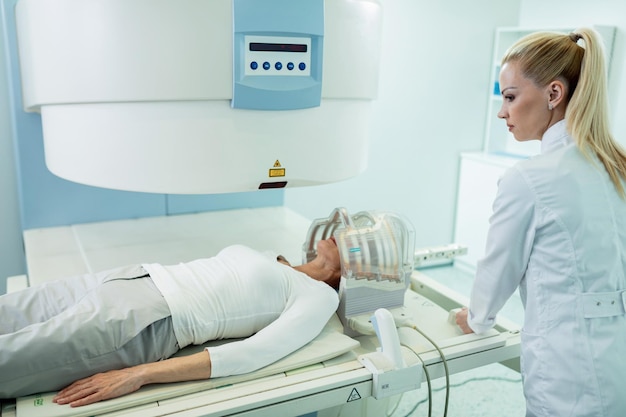 Female radiologist preparing a patient for MRI brain scan in the hospital