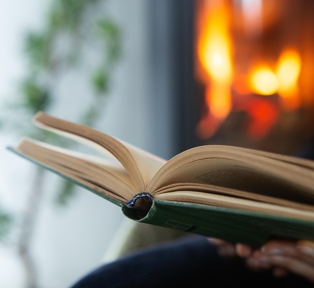 Foto donna che legge un libro accanto al camino accogliente stile di vita invernale