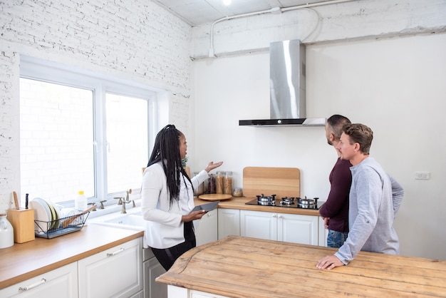 Female real estate agent showing gay couple around new house