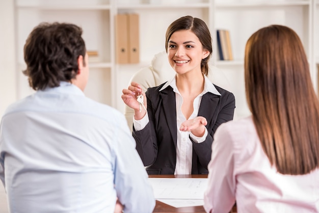 Female realtor with key and young couple from back.