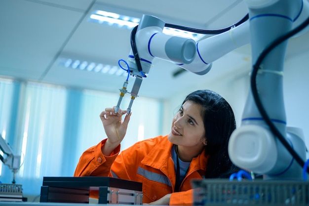 Foto ingegnere robotica femminile che lavora con la mano robotica di programmazione e manipolazione