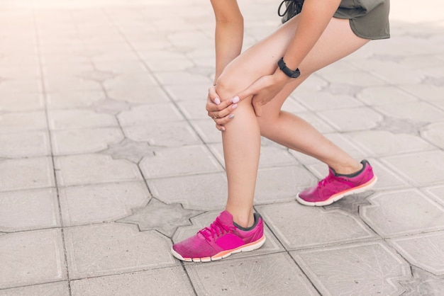 Foto corridore femminile che ha ferita al ginocchio che sta sul pavimento