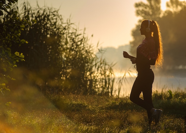 Female runner running in nature during sunrise