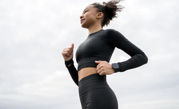 Женщина-бегунья занимается фитнесом на открытом воздухе, активные упражнения использует фитнес-часы