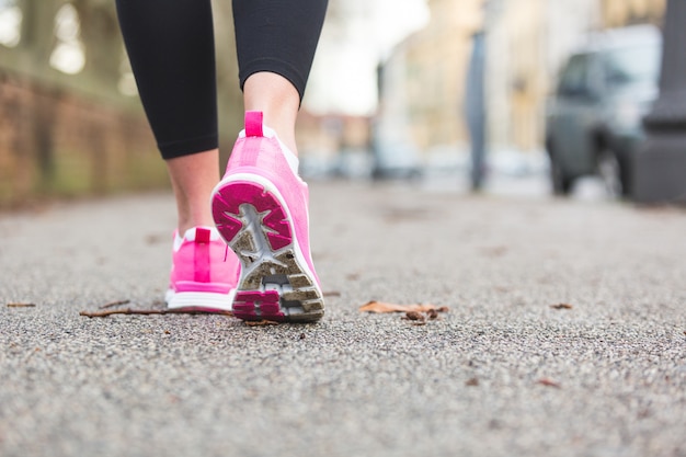 Female Runner Shoes closeup on the road, town setting. Shallow depth of Field, focus on rear shoe. 