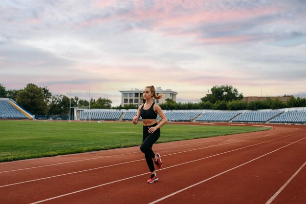 Female runner in sportswear jogging training on stadium Woman doing stretching exercise before running on outdoor arena