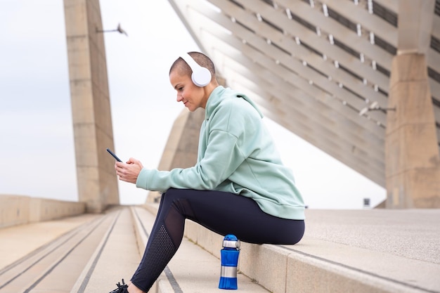 Photo a female runner takes a break to use an app on her smartphone outdoors