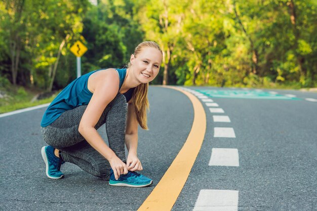 準備をしている若い女の子のランナーの外でジョギングの準備をしている彼女の靴を結ぶ女性ランナー