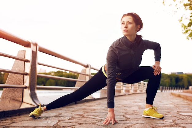 Female runner with beautiful figure doing stretching exercise before began her run