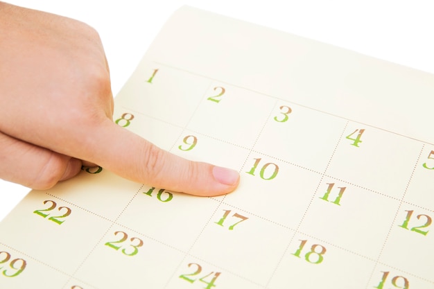 Female's finger showing date in a calendar on white background. number in the calendar