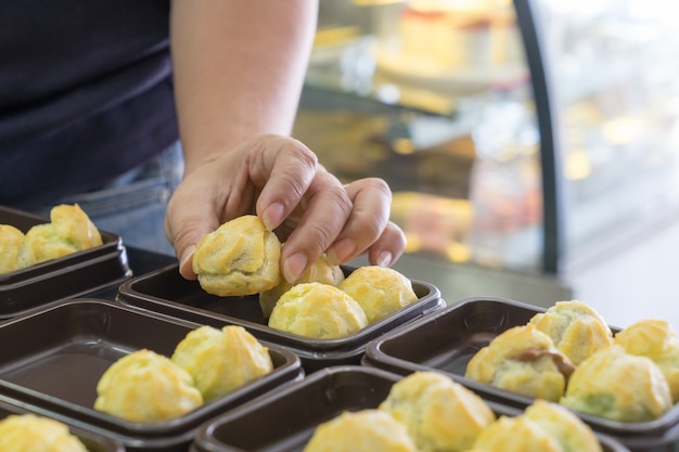 Female's hand decorate of choux pastry with cream