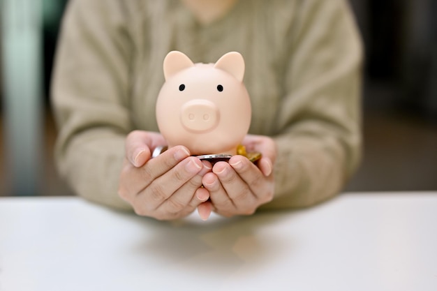 A female's hands holding a piggy bank and coins over the table Saving money financial