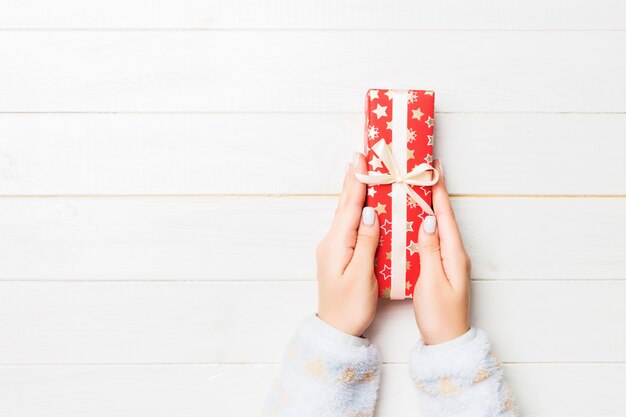 Female's hands holding striped gift box with colored ribbon