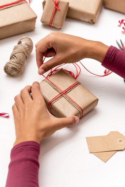 Foto mani della femmina che avvolgono i contenitori di regalo di natale