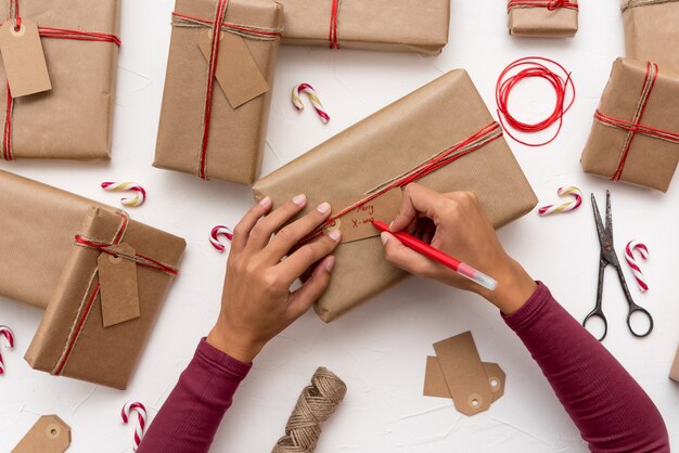 Foto mani della femmina scrivendo cartoline di natale su scatole regalo