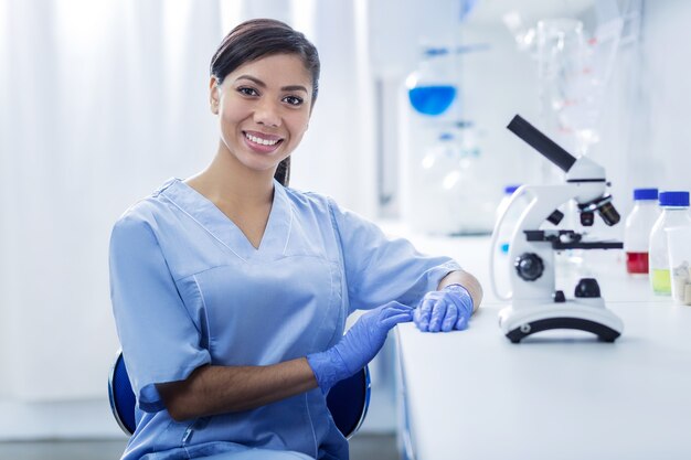 Female scientist. Happy cheerful nice woman looking at you and smiling while working as a scientist in the lab