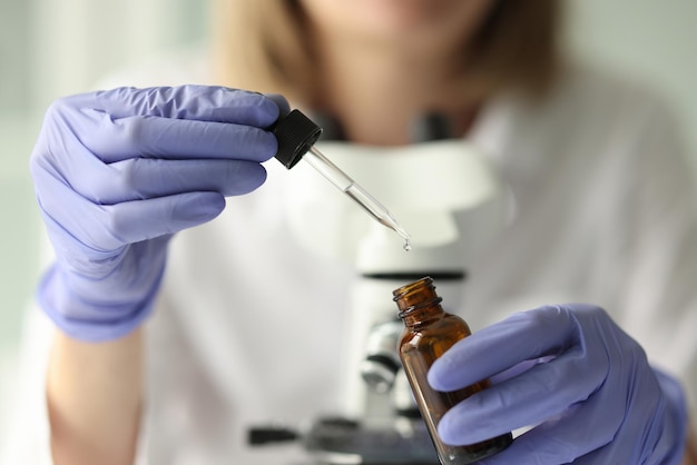 Female scientist holding pipette and vial close up woman in latex gloves taking liquid by