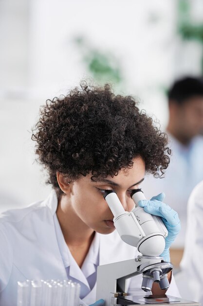 Female scientist looking through a microscope closeup