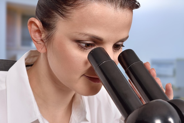 顕微鏡を通して見る女性科学者