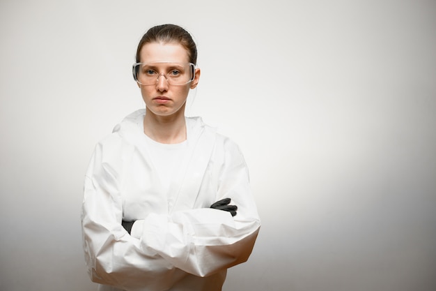 Женщина ученый в защитном снаряжении и очки остаются со скрещенными руками