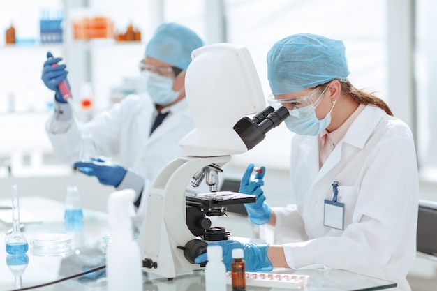 Female scientist sitting in front of a microscope