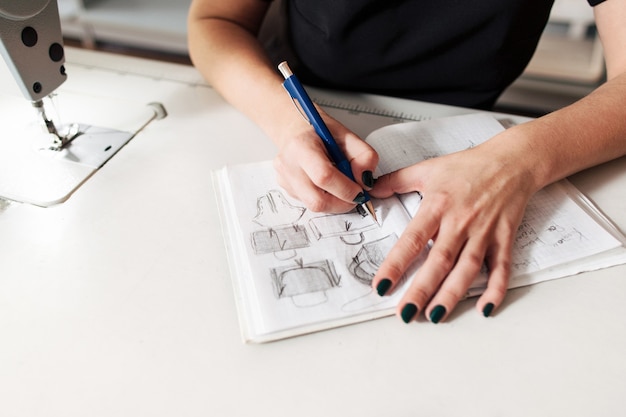 Female seamstress drawing sketch of bags in atelier