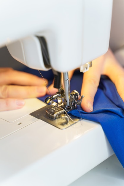 Female seamstress sewing or stitching fabric with professional machine